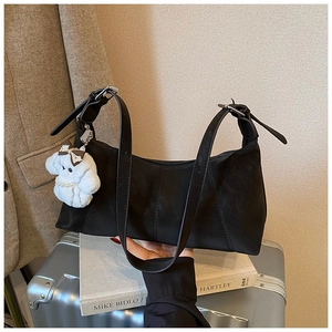 Detail of black crossbody bag with white puppy plush charm and adjustable silver buckle