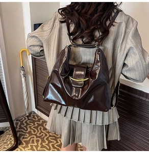 Detail of glossy chocolate brown leather bag with golden metallic hardware and slim straps