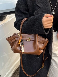 Brown leather handbag with pleated design and beaded charm shown in a street style shot