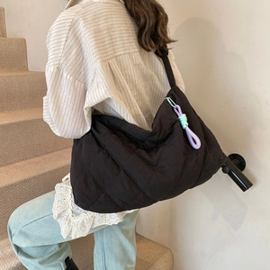 Detail of black quilted half-moon shoulder bag with colorful braided knot pendant