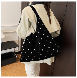 Detail of black suede hobo bag with silver metal studs shown worn on shoulder