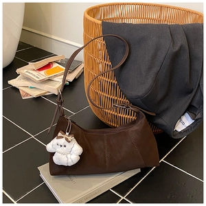 Macro view of vintage dark brown leather shoulder bag with plush dog charm and stitching
