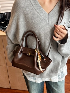 Fashionable dark brown leather handbag with wooden bead charm in a minimalist retro style