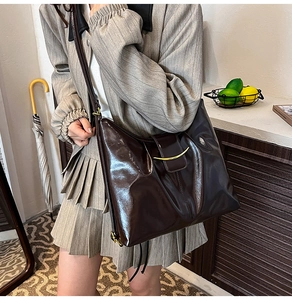 Detail of vintage dark brown tote bag featuring glossy patent leather and gold ring buckle