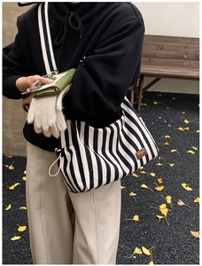 Détail du sac fourre-tout en toile à rayures noires et blanches avec écusson en cuir