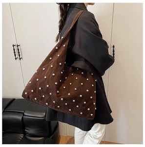 Detail view of large brown suede shoulder bag with decorative silver rivets on model