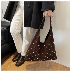 Detailed macro view of dark brown suede tote bag featuring metallic silver rivet ornaments