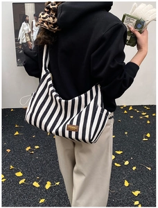 Détail du sac hobo en toile rayée noire et blanche avec étiquette en cuir marron