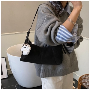 Detail of black matte shoulder bag with a cute white plush puppy pendant accessory