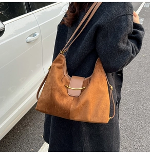 Close-up of vintage brown suede hobo bag with gold crescent metal clasp and leather strap