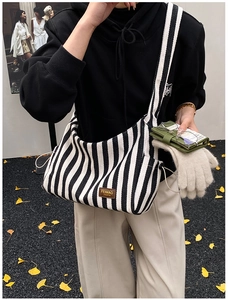 Détail du sac fourre-tout en toile à rayures avec bandoulière large et cordon latéral
