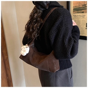 Detail of dark brown vintage faux leather shoulder bag with cute white bear plush charm