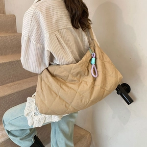 Detailed back view of a khaki quilted cloud bag worn by a model in a minimalist setting