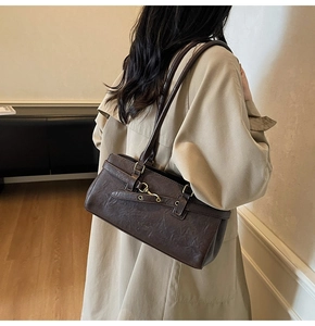 Close-up of a vintage dark brown shoulder bag worn with a chic light trench coat
