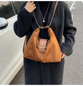 Close-up of brown suede hobo bag with golden crescent metal buckle on shoulder