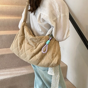 Detailed view of khaki quilted hobo bag with braided tassel worn by a model