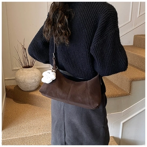 Dark brown matte leather dumpling bag with white floral charm worn by a model