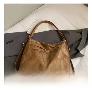 Detail showing the glossy brown pleated texture and strap buckle on a daily tote bag