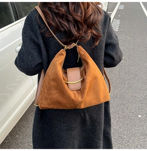 Close-up of vintage brown suede tote bag with metal clasp shown in a street setting