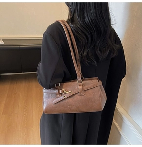 Detail of vintage dark brown faux leather shoulder bag with gold buckle and brand logo
