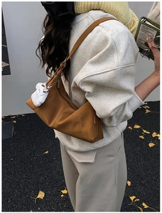 Detailed view of brown geometric crossbody bag with a cute white plush bear pendant