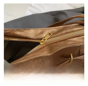 Close-up of golden zipper hardware and textured brown metallic fabric on a tote bag
