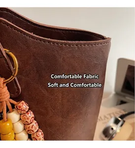 Dettaglio borsa in pelle marrone vintage con ciondolo a perline e cuciture di alta qualità