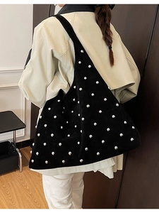 Black hobo shoulder bag with silver stud rivets and matte finish displayed on model