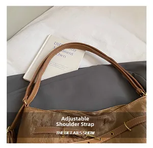Detail showing the adjustable shoulder strap with gold metal buckle on a brown tote bag