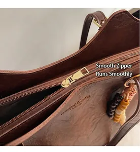 Dettaglio della borsa in pelle marrone con cerniera dorata e accessorio di perle