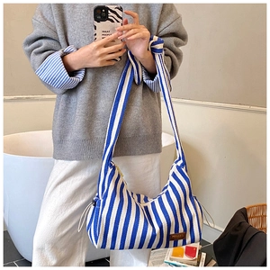 Détail d'un sac hobo en toile rayé bleu et blanc avec une large bandoulière réglable