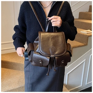 Detail view of vintage dark brown leather backpack with buckle straps and side pockets