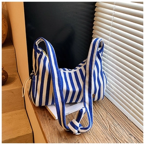 Détail du sac hobo en toile rayée bleu et blanc avec cordon et patch logo latéral