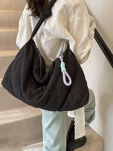 Chic black quilted shoulder bag with knotted strap and colorful tassel on model