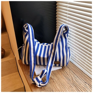 Détail d'un sac en toile à rayures bleues et blanches avec écusson logo en cuir brun