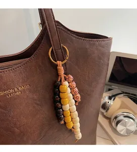 Dettaglio di un ciondolo boho con perline su borsa tote in pelle marrone scuro