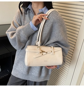 Detail shot of a creamy white hobo bag featuring fine leather texture and golden hardware
