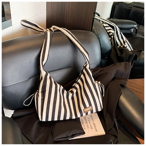 Détail du sac cabas en toile à rayures noires et blanches avec cordon et étiquette de marque