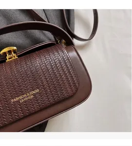 Detailed close-up of woven leather texture and gold buckle on dark brown crossbody bag