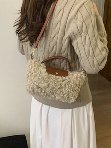 Sherpa fleece dumpling handbag with brown leather trim worn by model in beige sweater
