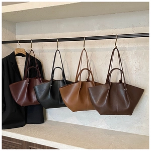 Row of minimalist leather tote bags in burgundy, black, brown, and coffee hanging on a rack