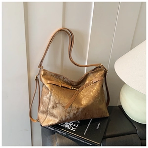 Detail showing the vertical metallic texture and buckle of a large bronze tote bag