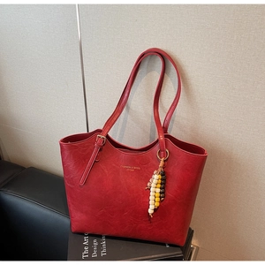 Dettaglio della borsa tote rossa con trama in pelle e nappina di perline di legno