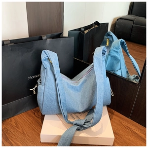 Détail du sac hobo en jean bleu avec large bandoulière nouée et cordon de serrage