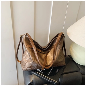 Detail of vintage brown tote bag with metallic texture and brass hardware on books