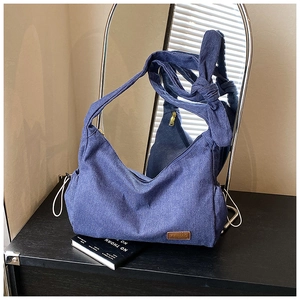 Détail du sac bandoulière en denim bleu avec bandoulière à nœud décoratif et zip en métal