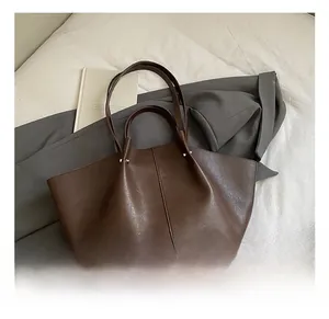 Detail view showing brown leather tote bag with stylish side pleats and silver metal studs