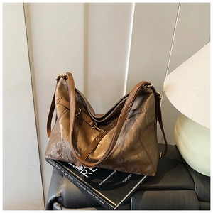 Chic bronze tote bag with metallic texture on design books under warm lamp light