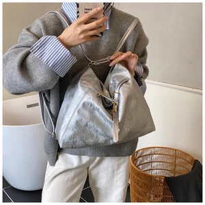 Detailed view of large silver metallic tote bag with drawstring and gold hardware