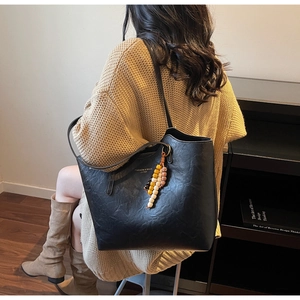 Dettaglio della borsa tote in pelle nera con ciondolo a perline colorate per il lavoro